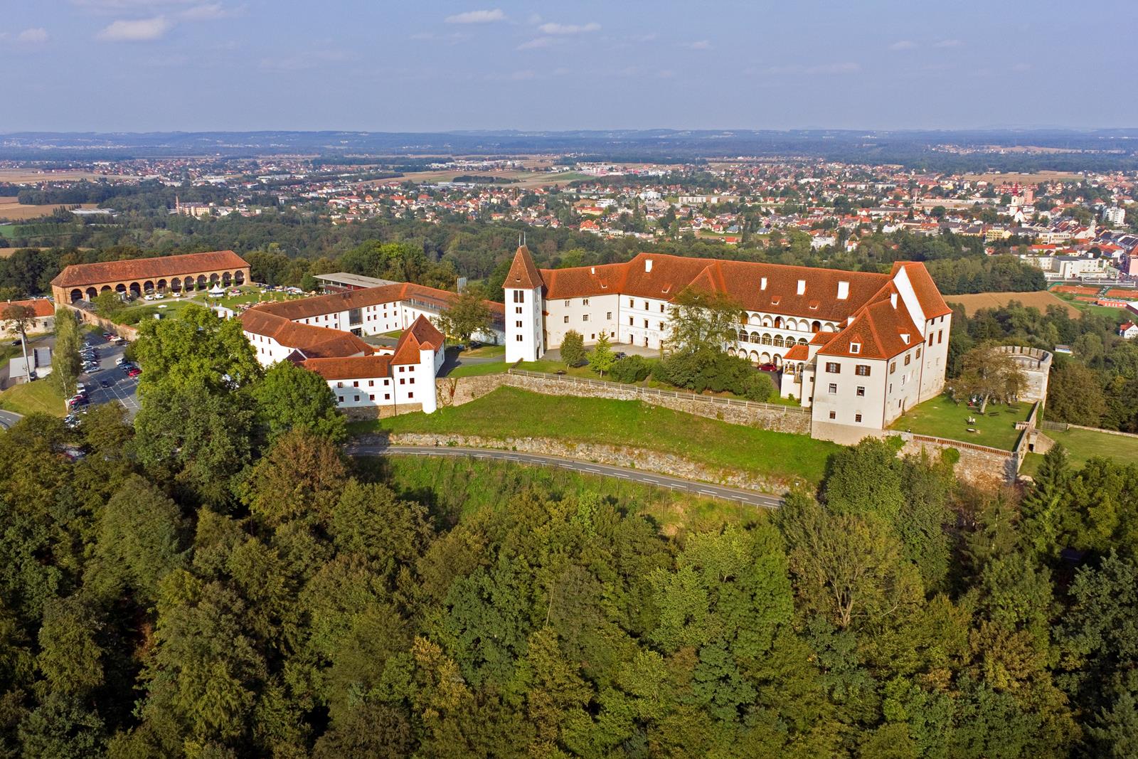 Flight shot of the surrounding of Schloss Seggau with view over Leibnitz and a forest