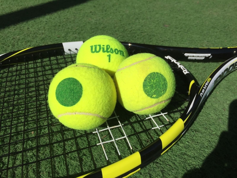 Tennischläger mit drei gelben Tennisbällen darauf