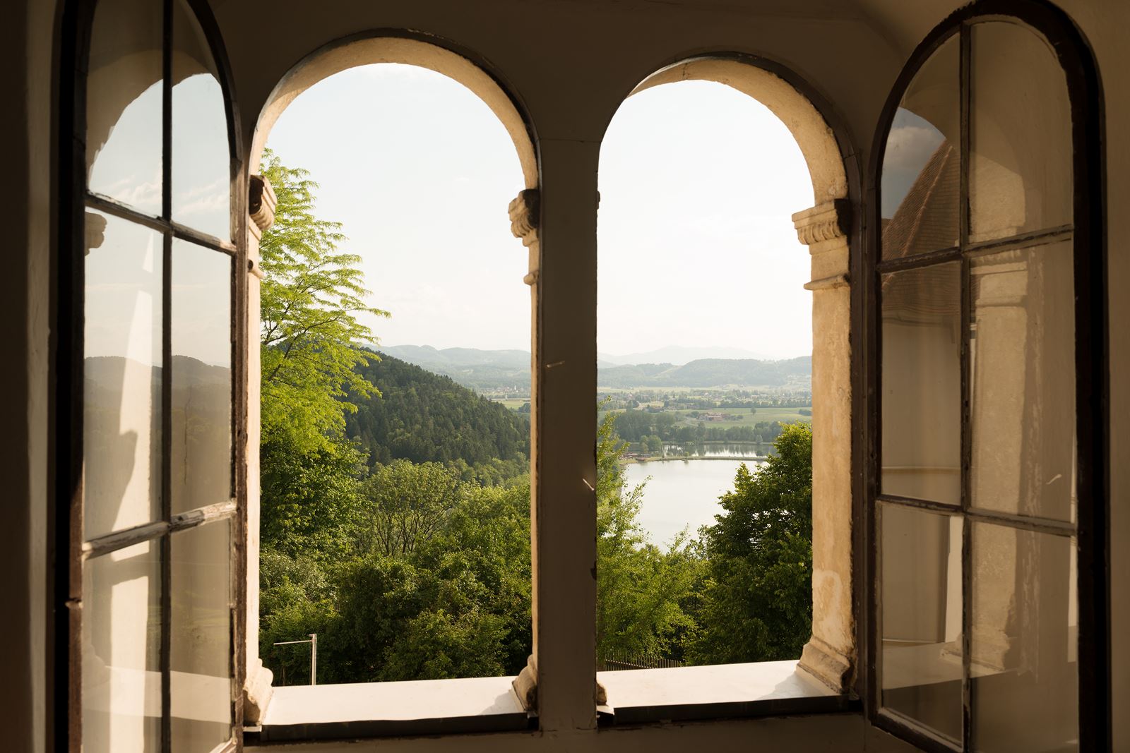 Der Blick führt aus einem Fenster des Oberschlosses auf den Sulmsee und die grüne Landschaft