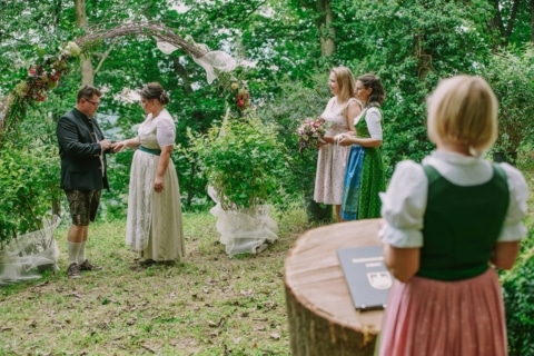 The groom puts the ring on the bride's finger at the forest wedding.