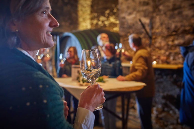 Episcopal Wine cellar-wine tasting at Seggau Castle. Ursula with a glass in the foreground smyling friendly